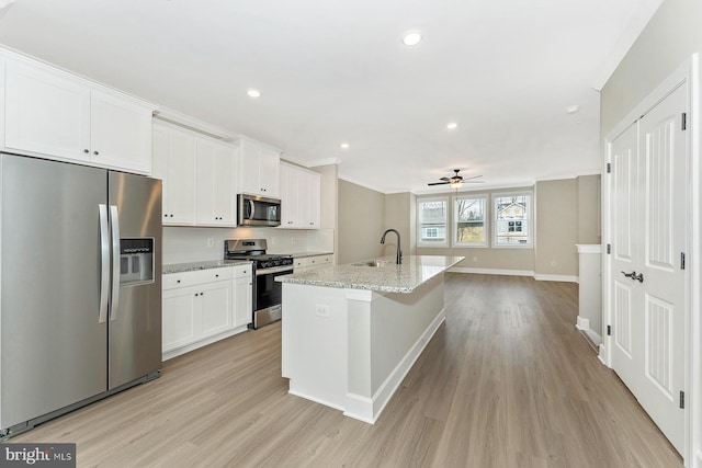 kitchen featuring stainless steel appliances, a sink, light wood finished floors, white cabinets, and ceiling fan