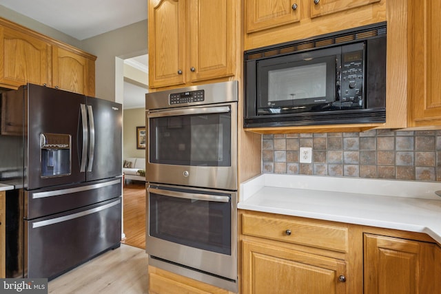 12649 Victory Lakes Loop, Bristow, VA 20136 - kitchen featuring black appliances, light wood-style floors, backsplash, and light countertops