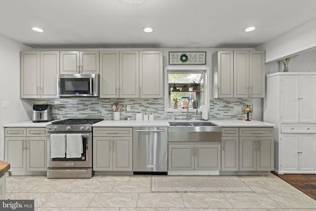 kitchen featuring stainless steel appliances, a sink, gray cabinetry, light countertops, and recessed lighting