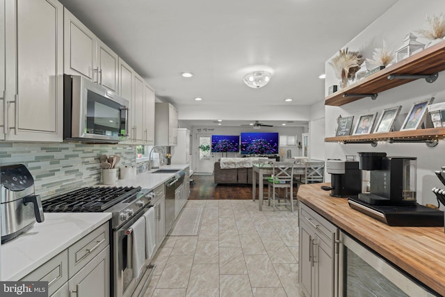 kitchen with stainless steel appliances, wood counters, open shelves, beverage cooler, and open floor plan
