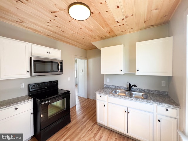 502 S Wayne St, Lewistown, PA 17044 - kitchen featuring stainless steel microwave, black range with electric stovetop, a sink, white cabinetry, and light wood-style flooring