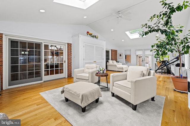 living area with a skylight, lofted ceiling, a ceiling fan, light wood-type flooring, and recessed lighting