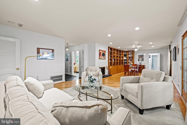 living room with a fireplace, light wood-style floors, recessed lighting, and plenty of natural light