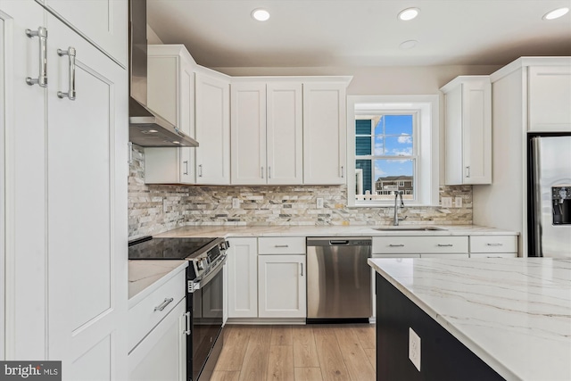 57 Bayside Dr, Fenwick Island, DE 19944 - kitchen with stainless steel appliances, a sink, wall chimney range hood, white cabinets, and recessed lighting