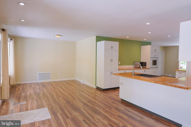175 Mountain Heights Rd, Front Royal, VA 22630 - kitchen featuring butcher block countertops, oven, white cabinets, wood finished floors, and recessed lighting