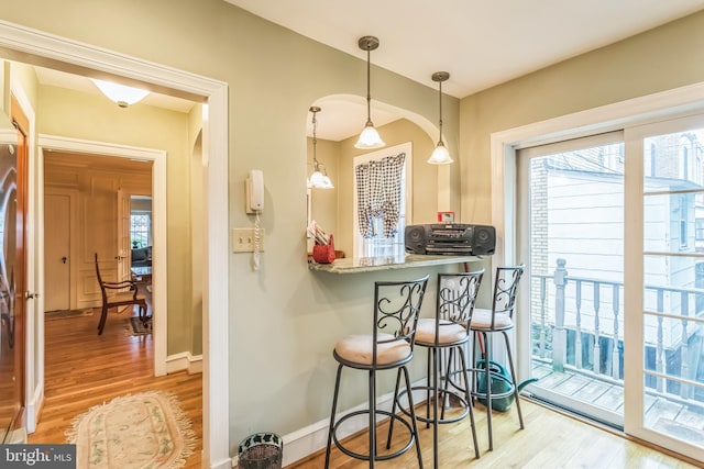 6427 Woodcrest Ave, Philadelphia, PA 19151 - kitchen featuring wood finished floors, a kitchen bar, pendant lighting, baseboards, and arched walkways