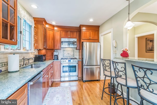 6427 Woodcrest Ave, Philadelphia, PA 19151 - kitchen with appliances with stainless steel finishes, a sink, light stone countertops, arched walkways, and light wood-type flooring
