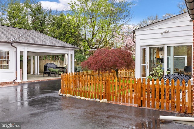 view of property exterior with a shingled roof and a patio