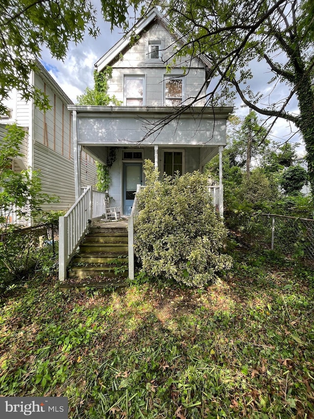 view of front of property with a porch and fence