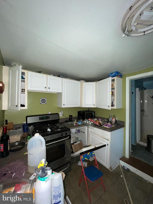 kitchen featuring stainless steel range with gas stovetop, white cabinetry, and open shelves