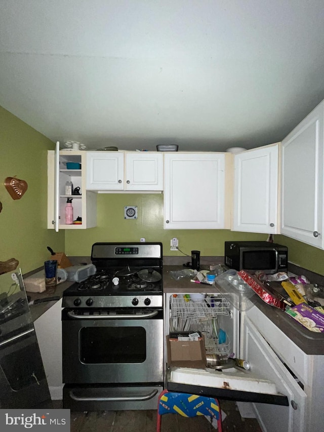 kitchen with stainless steel gas range oven, black microwave, white cabinetry, and dark countertops