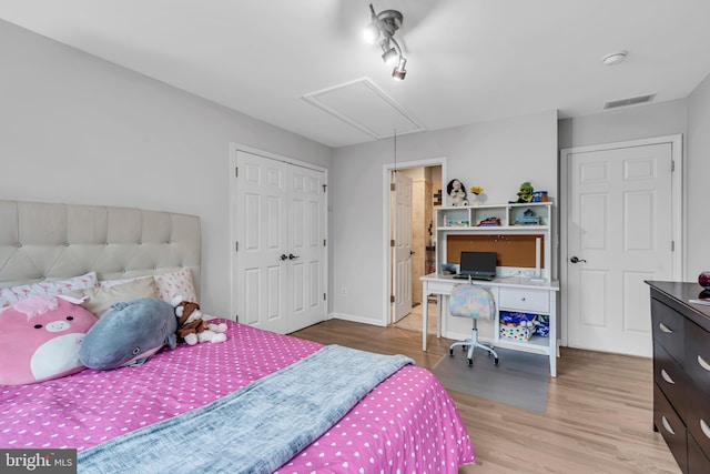 bedroom with attic access, wood finished floors, and a closet