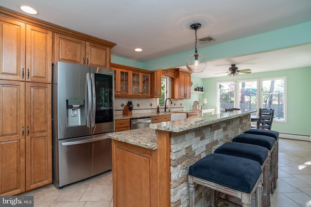 303 N Elm Ave, Newtown, PA 18940 - kitchen featuring appliances with stainless steel finishes, brown cabinets, light tile patterned flooring, light stone countertops, and recessed lighting