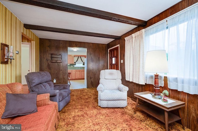 carpeted living area with wooden walls and beam ceiling