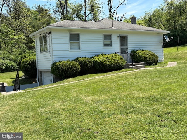 view of front of property featuring an attached garage, a chimney, and a front lawn