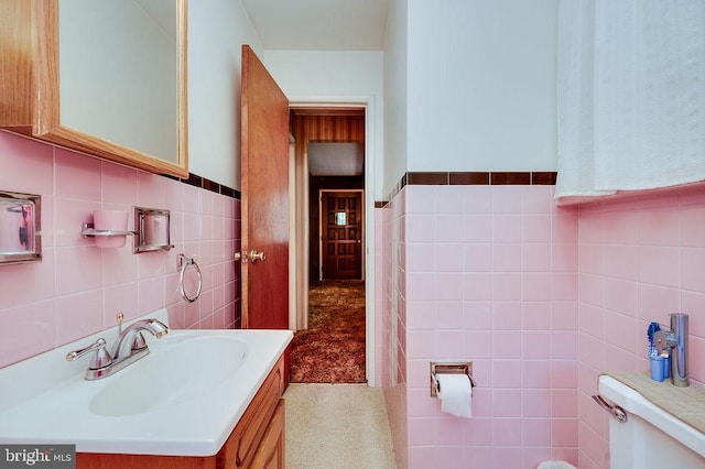 bathroom with tile walls, vanity, and a wainscoted wall