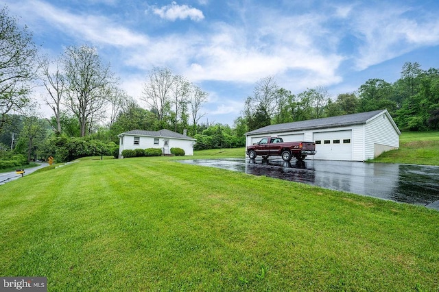 view of grassy yard with a detached garage, an outbuilding, and view of wooded area