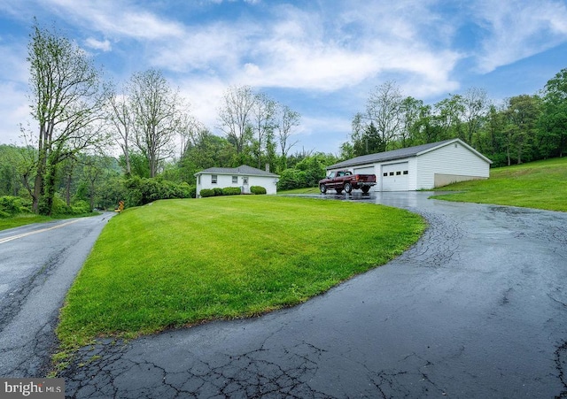 view of front of home with a garage, a front lawn, and an outbuilding