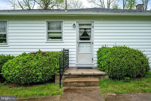 entrance to property featuring roof with shingles