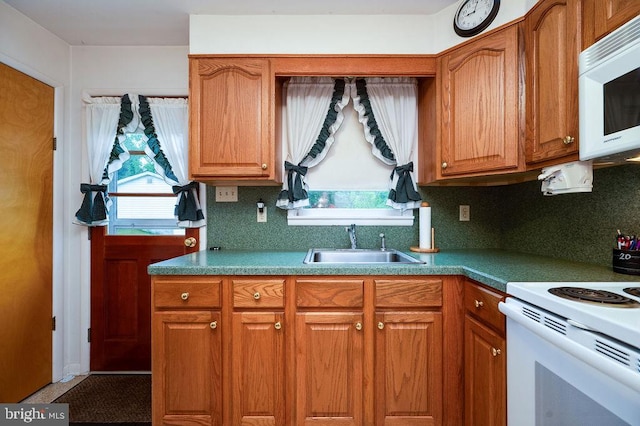kitchen with white appliances, a sink, and brown cabinetry