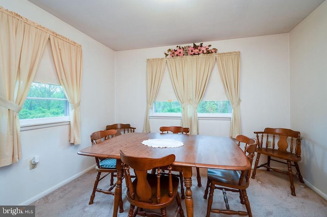 dining area featuring light carpet and baseboards