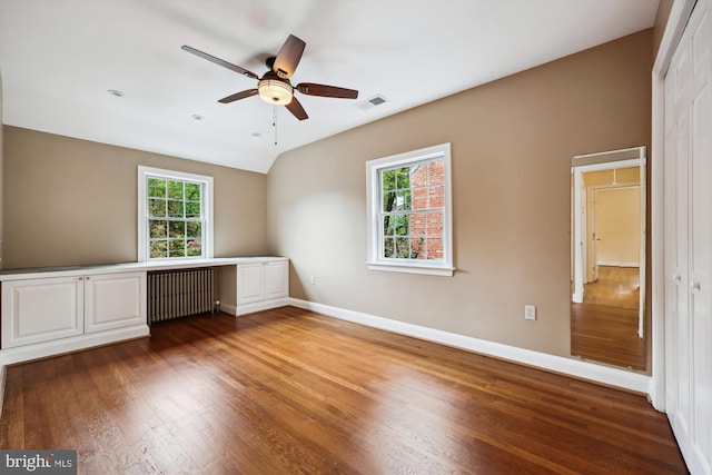 unfurnished bedroom with radiator, hardwood / wood-style floors, multiple windows, and baseboards