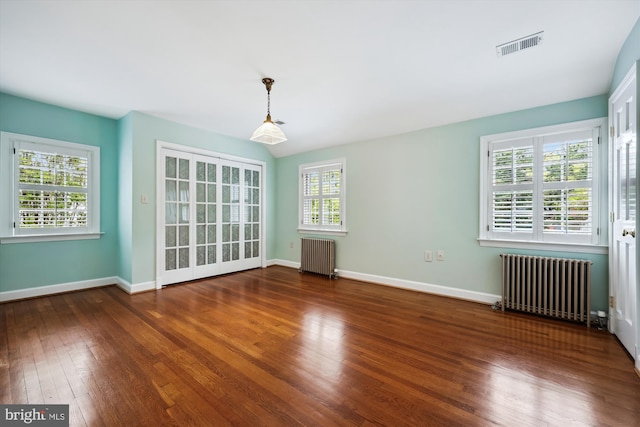 spare room featuring radiator, hardwood / wood-style flooring, and baseboards