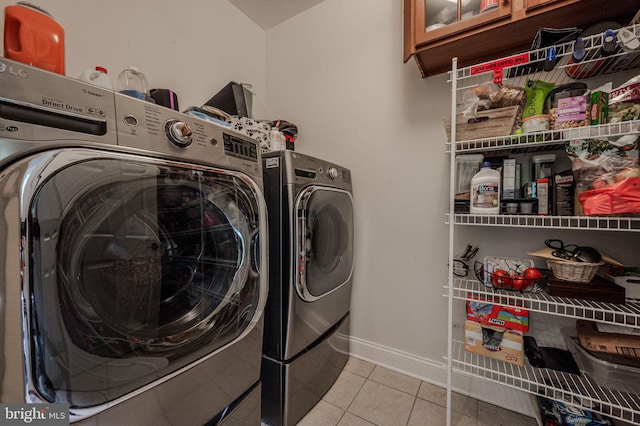 washroom featuring separate washer and dryer, light tile patterned floors, and baseboards
