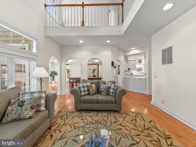 37 Sussex St, Rehoboth Beach, DE 19971 - living room with arched walkways, light wood-type flooring, a high ceiling, and baseboards