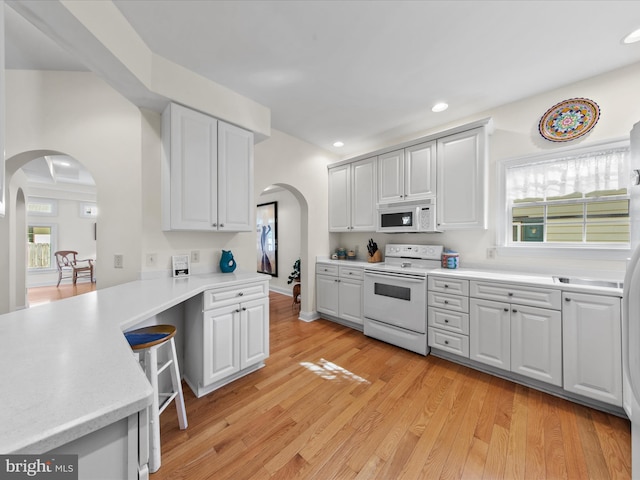 37 Sussex St, Rehoboth Beach, DE 19971 - kitchen with white appliances, arched walkways, light countertops, recessed lighting, and light wood-style flooring