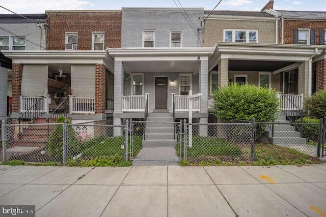 view of property featuring a porch, stairs, brick siding, and a gate