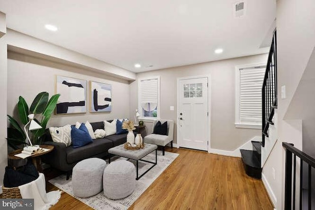 living room featuring stairs, light wood-style flooring, recessed lighting, and baseboards