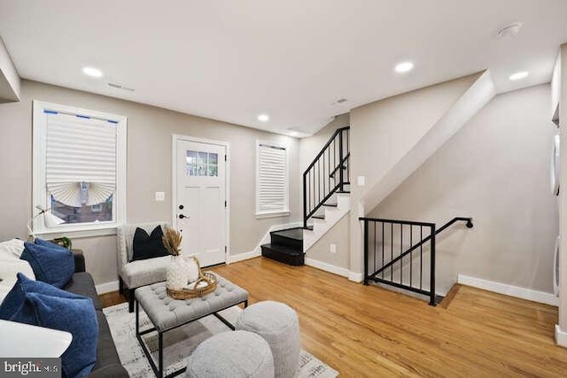 living room with wood finished floors, baseboards, recessed lighting, and stairs