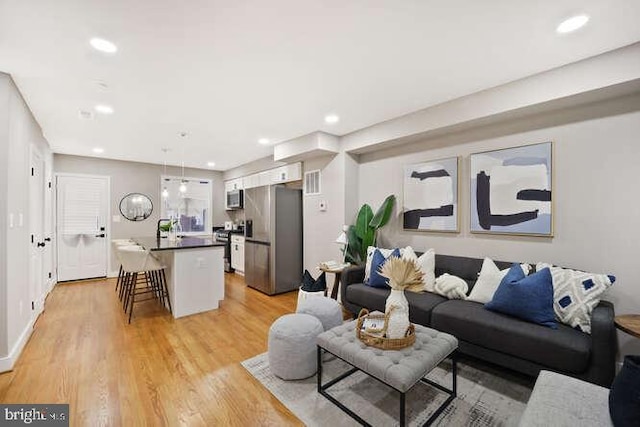 living room with light wood-type flooring and recessed lighting