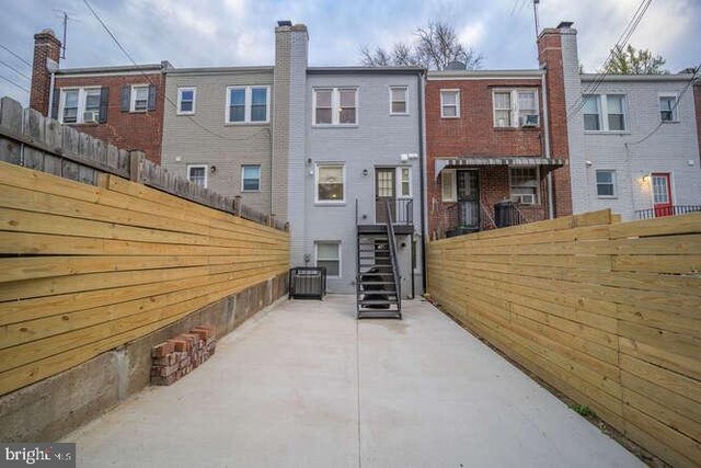 rear view of house featuring fence, brick siding, and a patio area