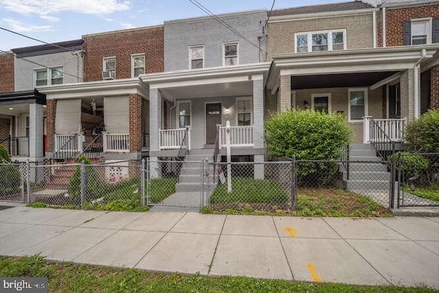 townhome / multi-family property with a porch, a gate, and brick siding