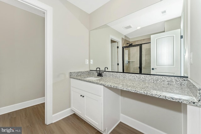 bathroom featuring a shower stall, wood finished floors, vanity, and baseboards