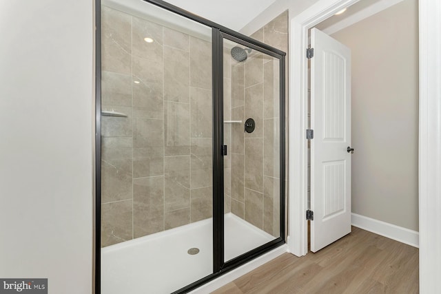 bathroom with a stall shower, wood finished floors, and baseboards