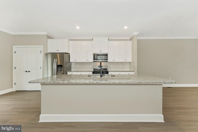 kitchen featuring stainless steel appliances, crown molding, a center island with sink, a sink, and white cabinets