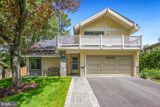 view of front of house with a balcony, asphalt driveway, stone siding, and an attached garage