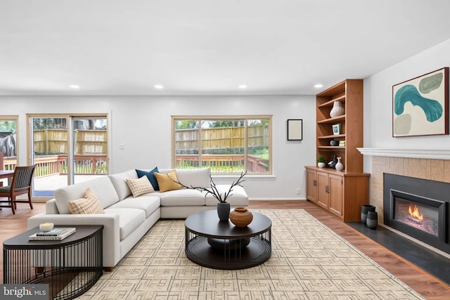 living area with wood finished floors, recessed lighting, a fireplace, and baseboards