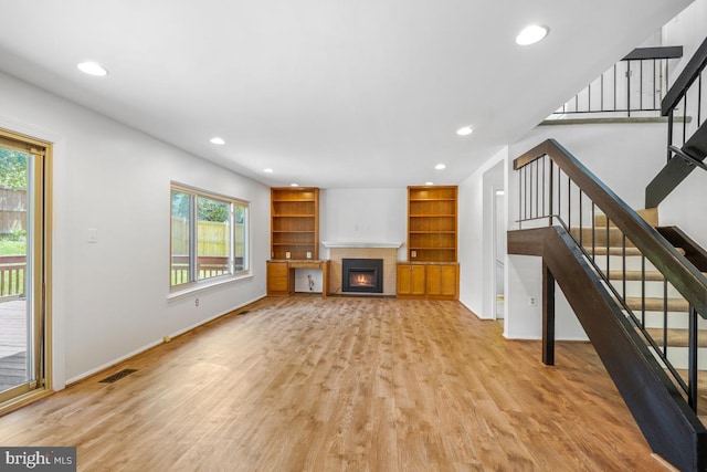unfurnished living room featuring light wood finished floors, baseboards, recessed lighting, and stairs