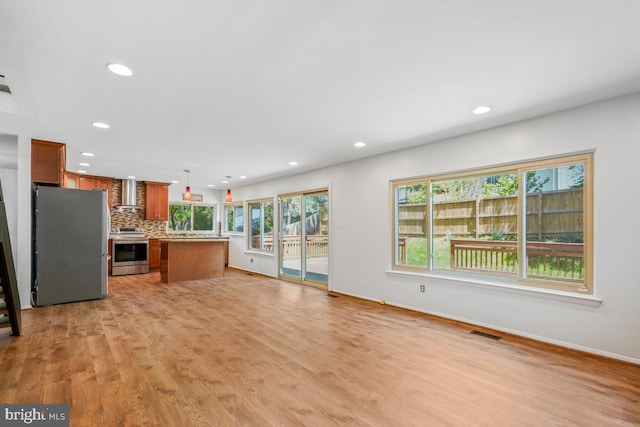 unfurnished living room with recessed lighting, light wood-style flooring, and baseboards