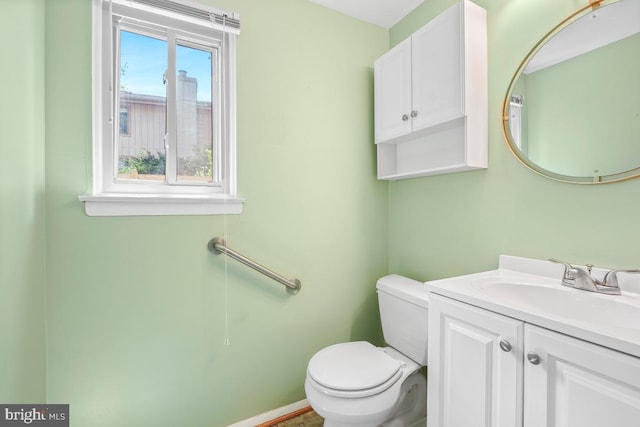 half bathroom featuring toilet, vanity, and baseboards