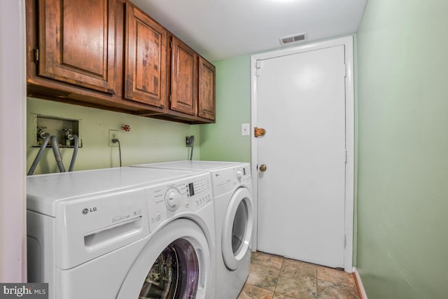 laundry area with cabinet space, washing machine and dryer, and stone finish floors