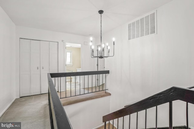 stairs with a chandelier, carpet flooring, and baseboards