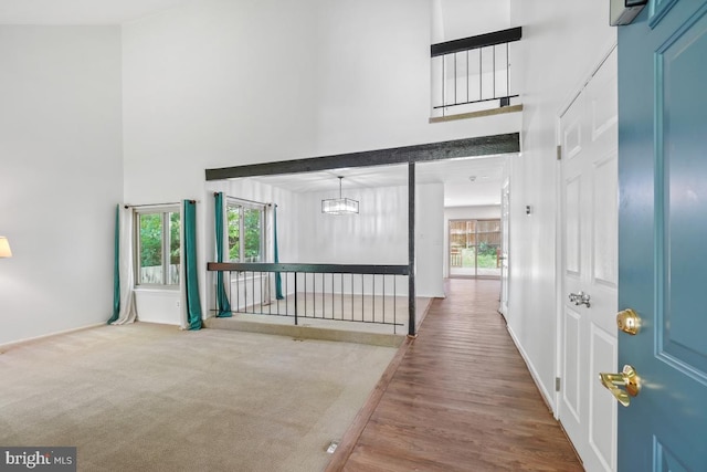 foyer with a towering ceiling, plenty of natural light, wood finished floors, a chandelier, and baseboards
