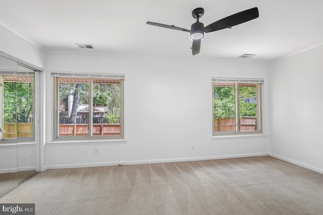 empty room with crown molding, healthy amount of natural light, carpet, and baseboards