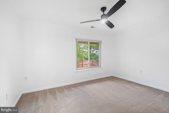 carpeted empty room featuring ceiling fan, baseboards, and crown molding