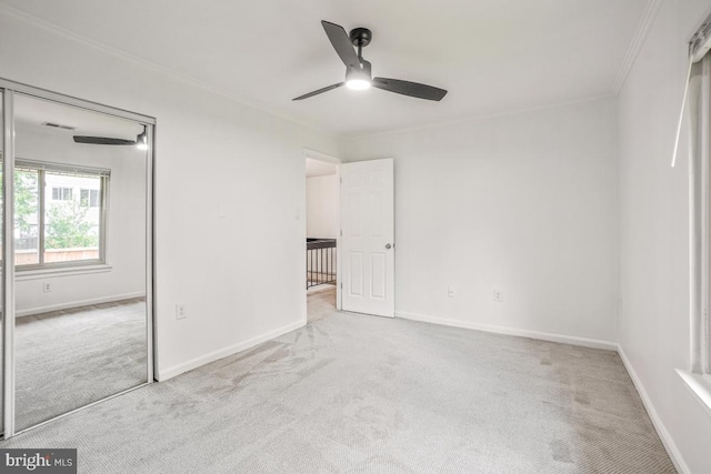 unfurnished bedroom featuring carpet, crown molding, baseboards, a closet, and a ceiling fan